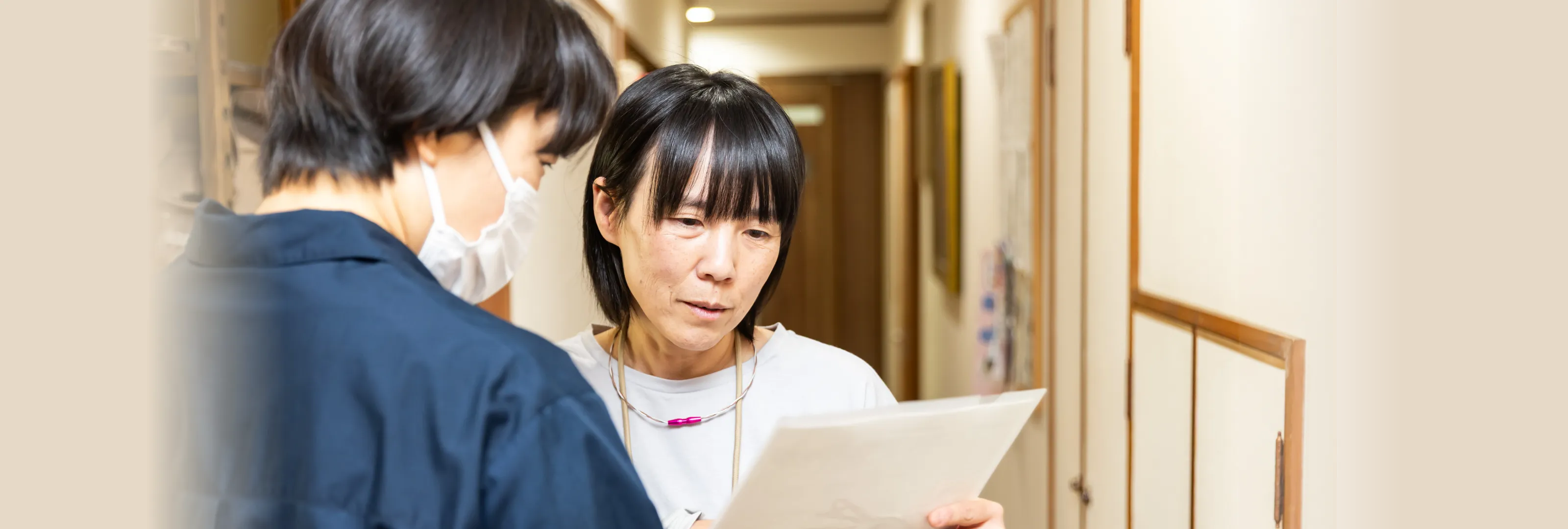 廊下で書類を確認しながら打ち合わせをする介護スタッフたち