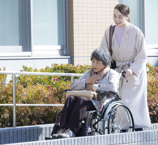 スロープで車椅子の高齢女性を優しく押す介護スタッフ
