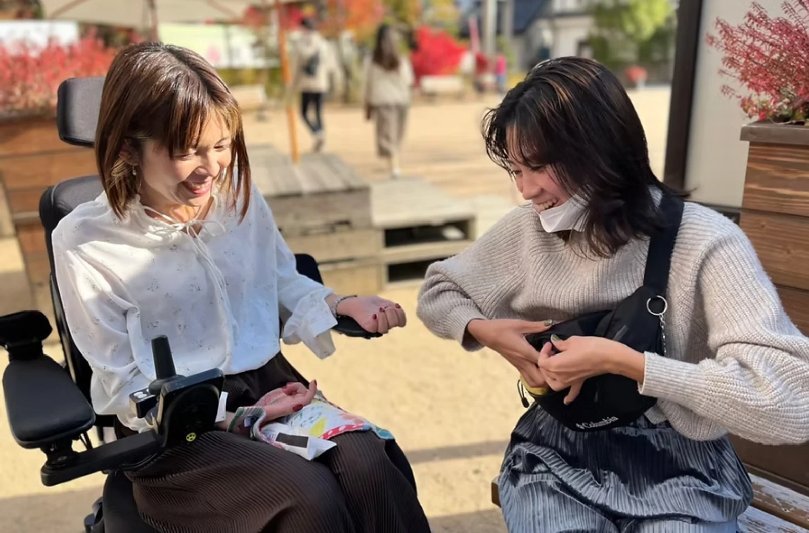 電動車椅子の女性と屋外で楽しそうに会話する介護スタッフ