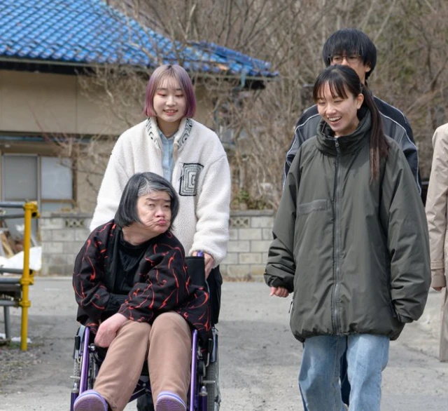 車椅子に乗る利用者とともに屋外を散歩する介護スタッフたち