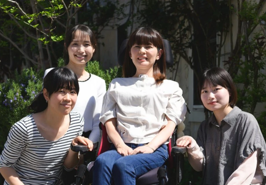 車椅子の女性を囲んで笑顔で記念撮影をする介護スタッフたち
