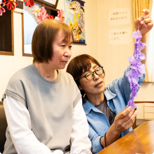 利用者と一緒に手芸作品を見る介護スタッフ