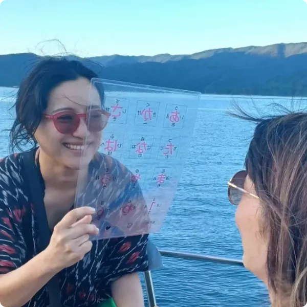 海を背景に文字ボードでコミュニケーションをとる女性たち