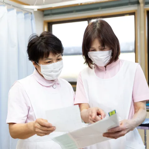 マスクを着用し書類を確認しながら打ち合わせをする看護師