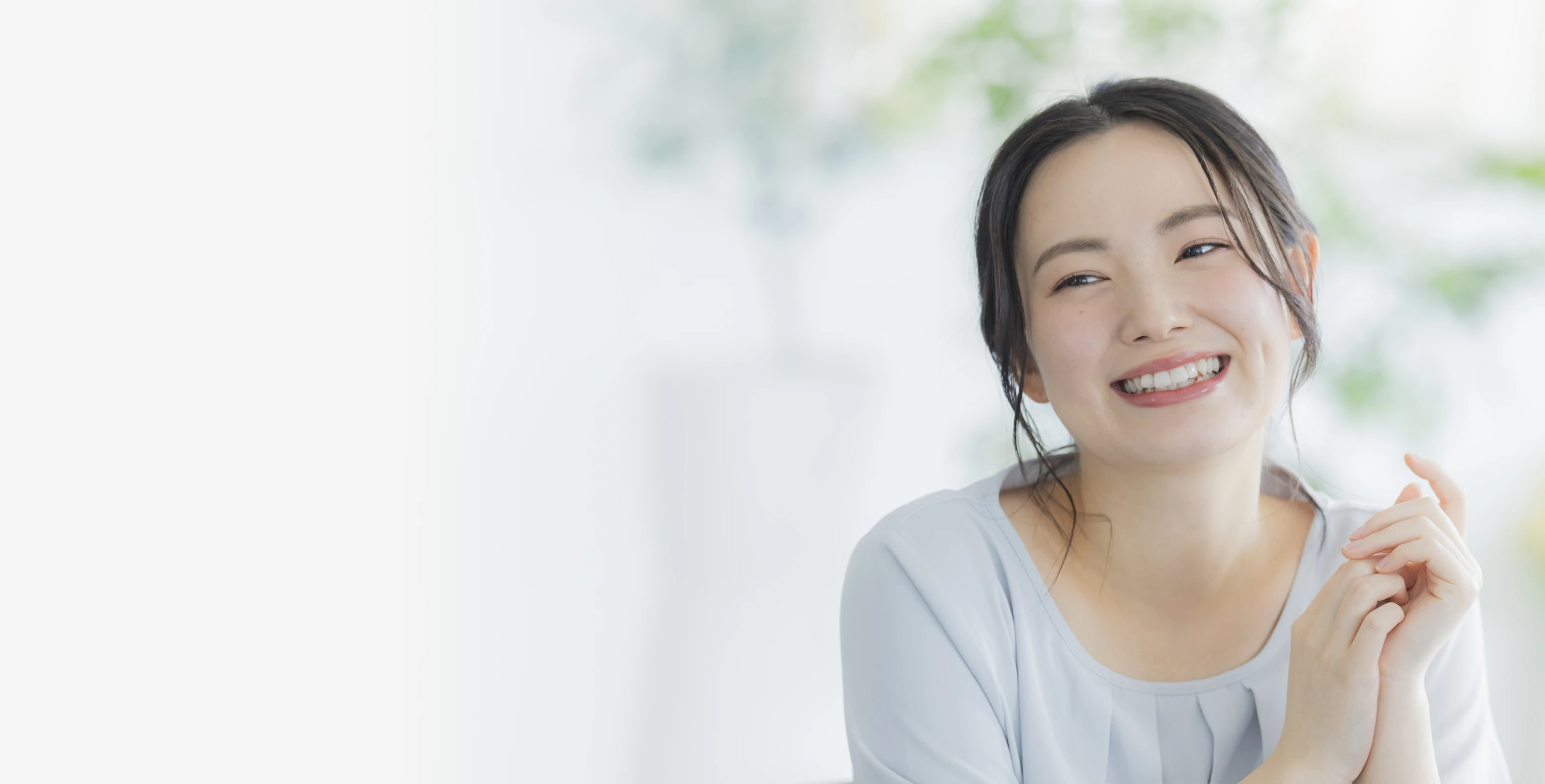 明るい背景で優しく微笑む若い女性のメインビジュアル