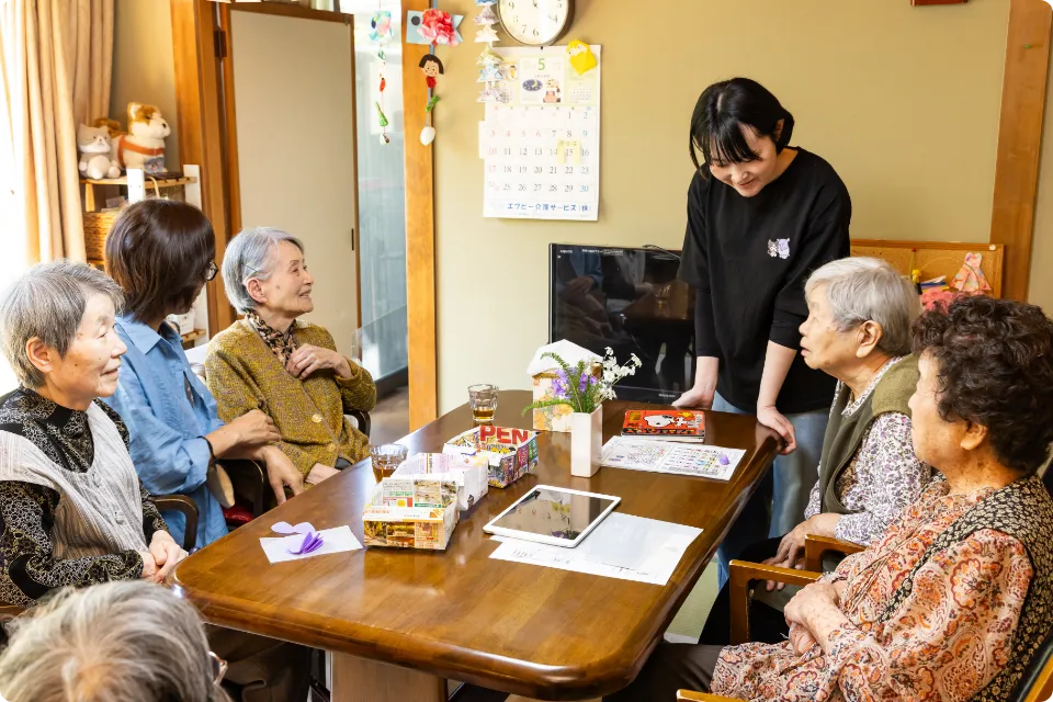 テーブルを囲んで利用者の高齢者と歓談する介護スタッフ