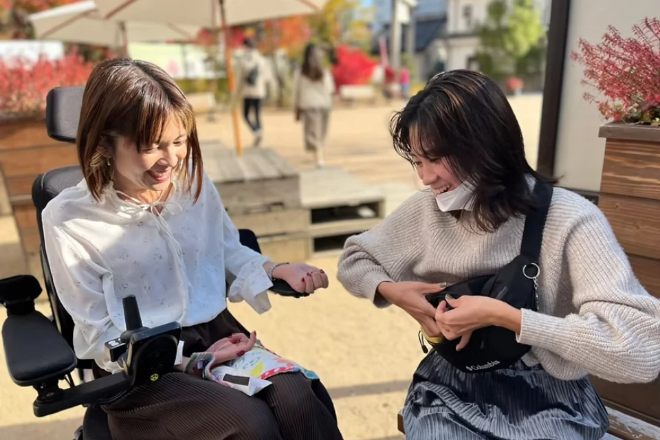 屋外で電動車椅子の女性と笑顔で会話する介護スタッフ