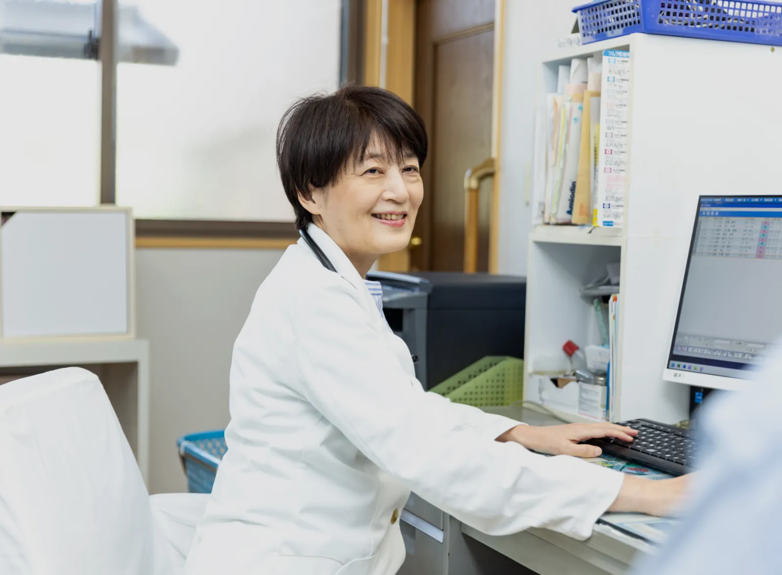 パソコンの前で笑顔を見せる女性医師